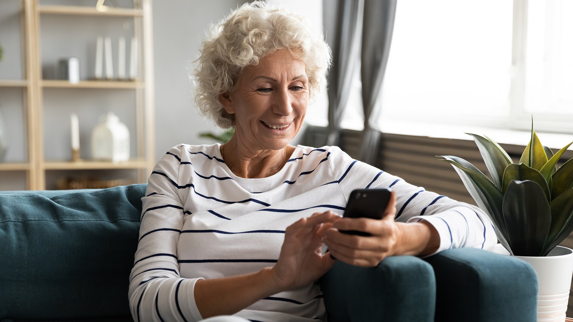 An elderly lady smiling while using mobile in independent living for seniors