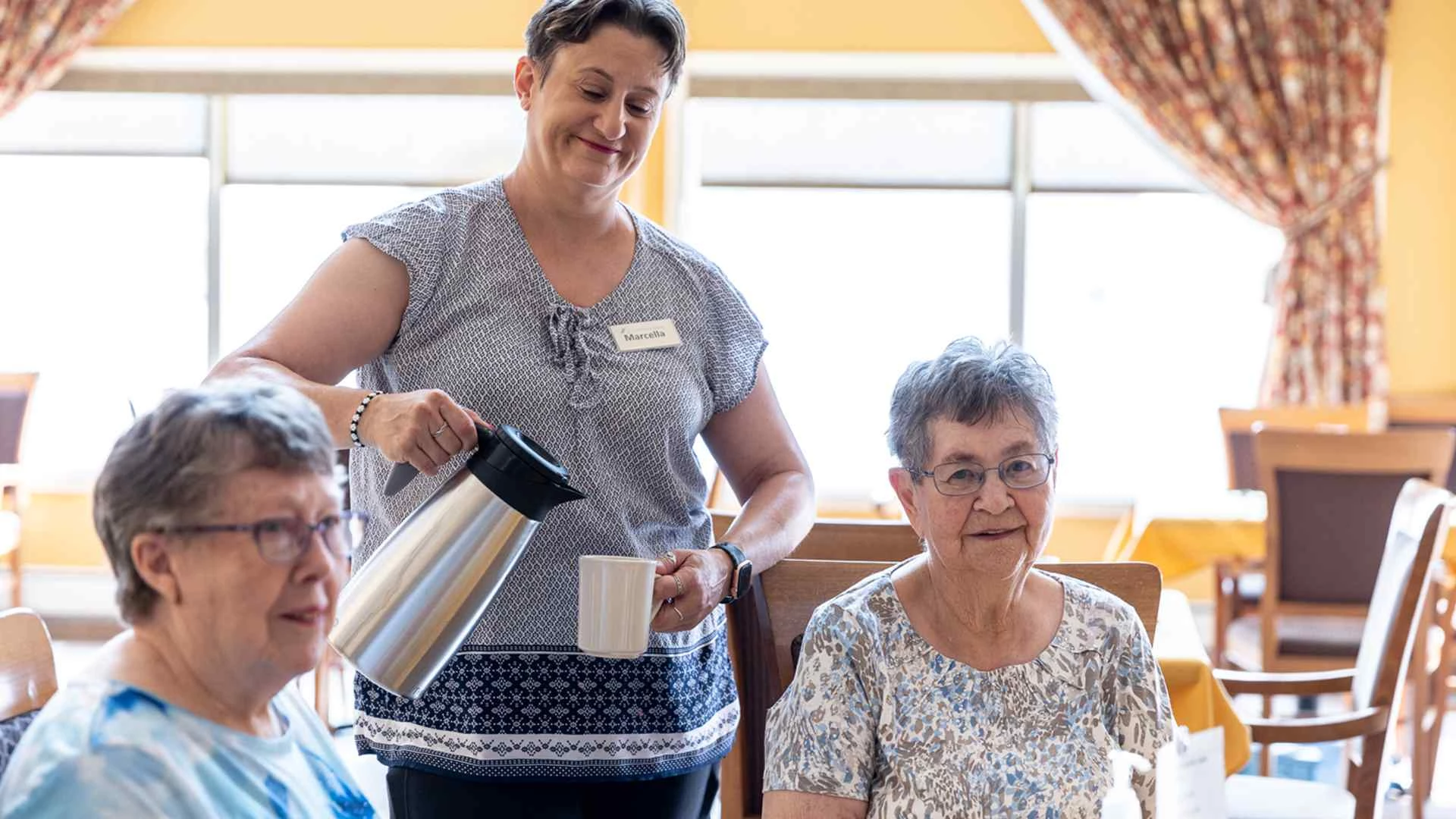 At the CV residence, a woman serves two old women coffee.