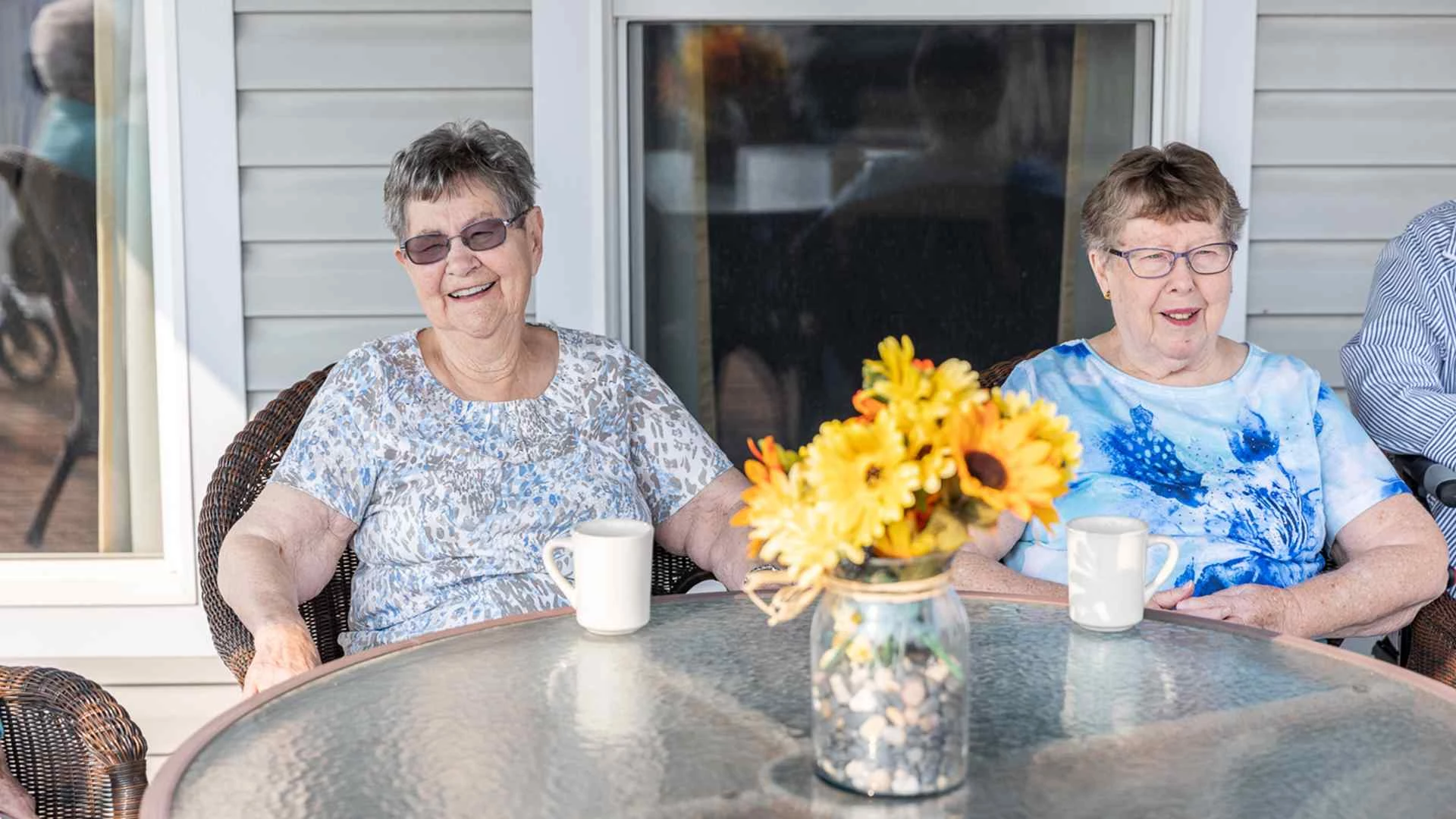 A couple of elderly ladies smiling while drinking coffee