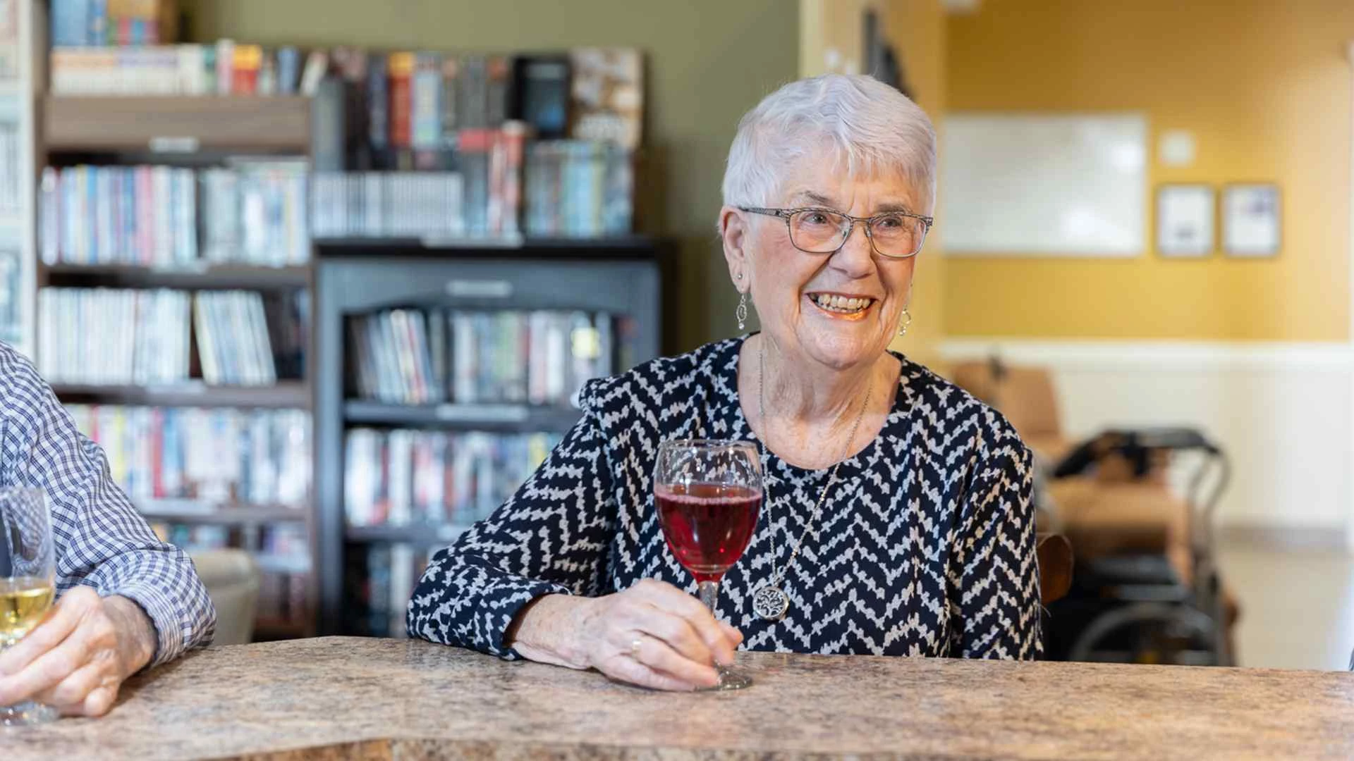 An elderly lady smiling while enjoying coffee